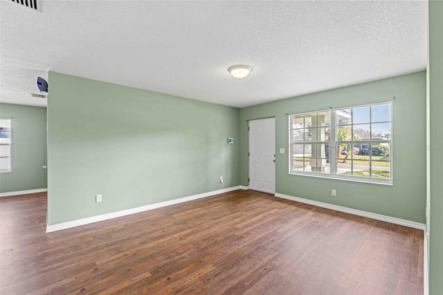 unfurnished room featuring baseboards, dark wood finished floors, and a textured ceiling