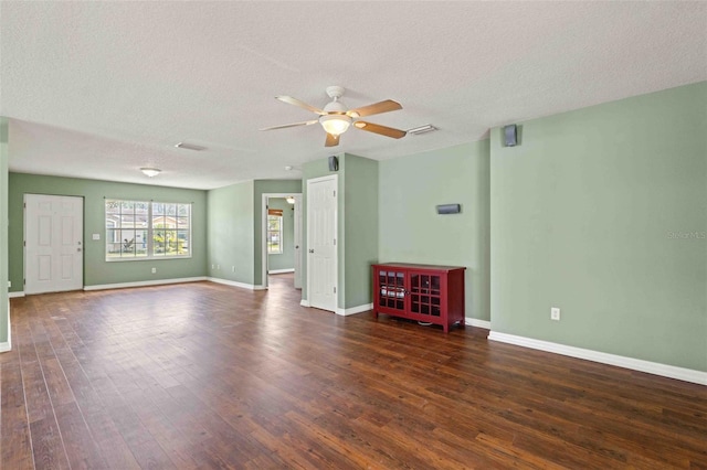 empty room with dark wood-style flooring, visible vents, a textured ceiling, and baseboards