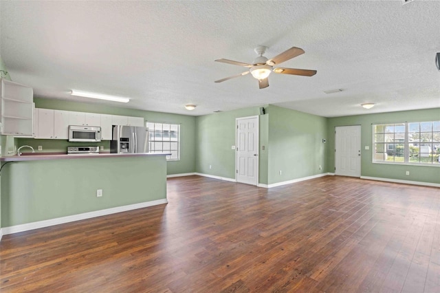 unfurnished living room with baseboards, visible vents, ceiling fan, dark wood-type flooring, and a textured ceiling