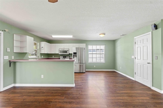 kitchen featuring stainless steel appliances, a peninsula, open shelves, and white cabinets