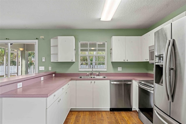 kitchen featuring white cabinets, stainless steel appliances, a healthy amount of sunlight, open shelves, and a sink