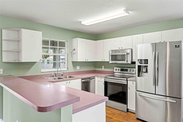 kitchen featuring white cabinets, a breakfast bar area, a peninsula, stainless steel appliances, and a sink