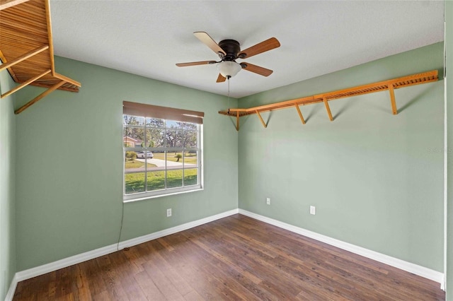 spare room with a ceiling fan, baseboards, and dark wood-type flooring