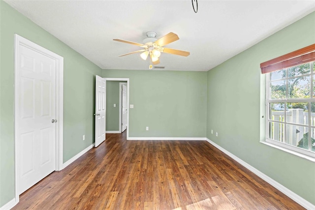 empty room with a ceiling fan, dark wood-style flooring, and baseboards