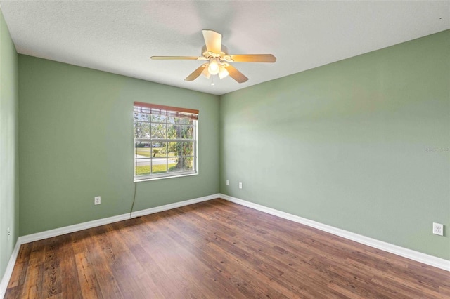 empty room featuring a textured ceiling, baseboards, dark wood finished floors, and a ceiling fan