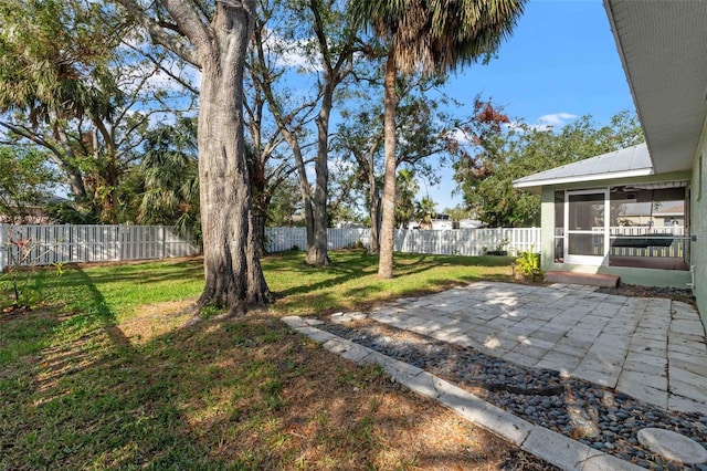 view of yard featuring a sunroom, a fenced backyard, and a patio