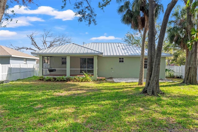 back of property featuring a sunroom, a fenced backyard, a yard, and stucco siding