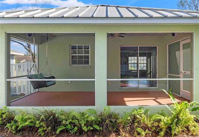 back of house with metal roof, a patio, a sunroom, stucco siding, and a standing seam roof