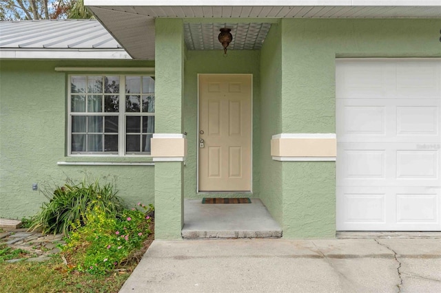 doorway to property with metal roof, a standing seam roof, and stucco siding