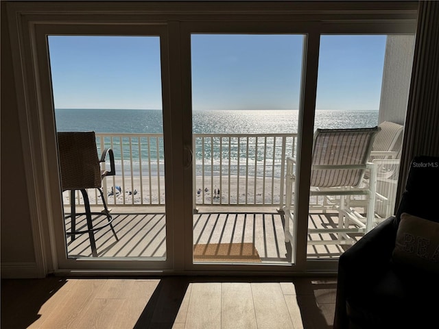 doorway to outside with hardwood / wood-style floors, a water view, and a view of the beach