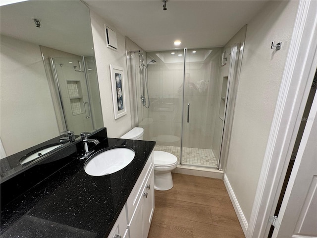 bathroom with hardwood / wood-style flooring, vanity, toilet, and a shower with shower door