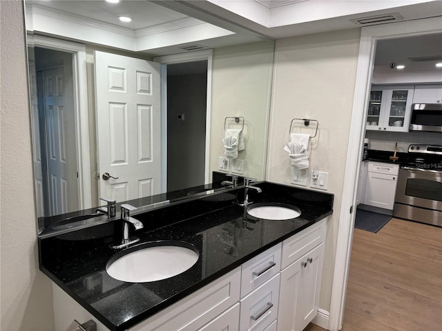 bathroom with a raised ceiling, backsplash, crown molding, hardwood / wood-style floors, and vanity