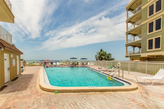 view of swimming pool with a patio and a water view