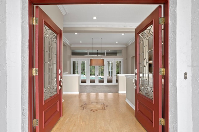 foyer with ornamental molding, light hardwood / wood-style floors, and french doors