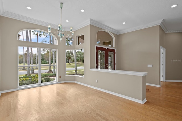 unfurnished room featuring crown molding, light hardwood / wood-style floors, and a notable chandelier