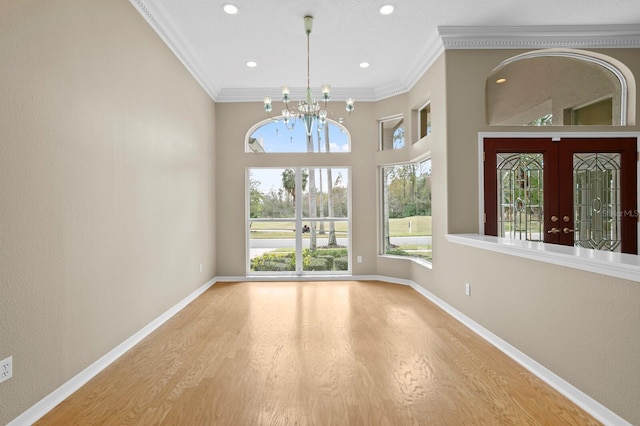 interior space featuring french doors, an inviting chandelier, ornamental molding, and wood-type flooring