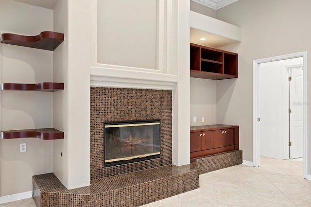 living room with light tile patterned floors, crown molding, and a tile fireplace