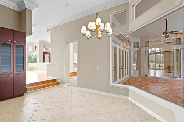 unfurnished dining area with a wealth of natural light, light tile patterned floors, crown molding, and ceiling fan with notable chandelier