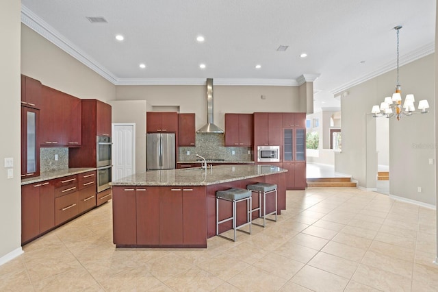 kitchen with tasteful backsplash, wall chimney range hood, a spacious island, crown molding, and appliances with stainless steel finishes