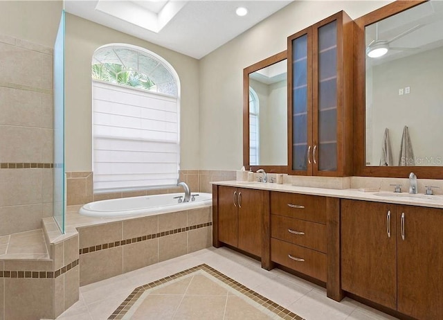 bathroom featuring ceiling fan, vanity, tile patterned flooring, and tiled tub