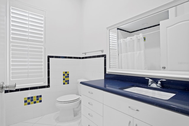 bathroom with toilet, tile walls, tile patterned floors, vanity, and curtained shower