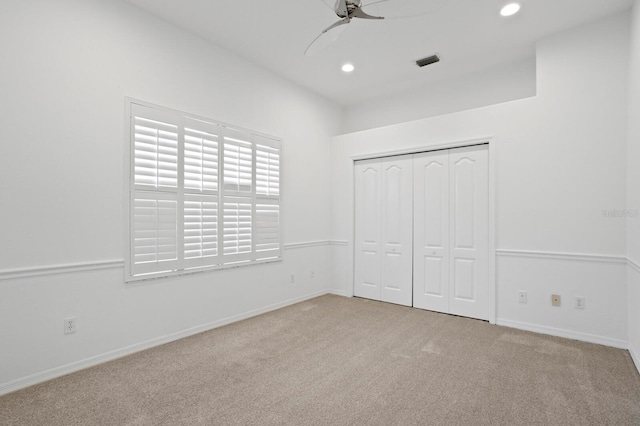 unfurnished bedroom with ceiling fan, light colored carpet, and a closet