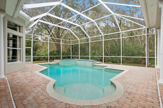 view of pool with a lanai, a patio, and an in ground hot tub