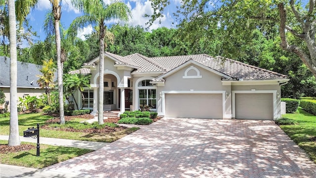10106 Radcliffe Dr, Tampa, FL 33626 - mediterranean / spanish house with an attached garage, decorative driveway, stucco siding, and a tile roof