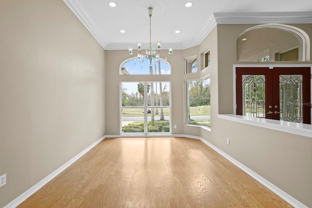 10106 Radcliffe Dr, Tampa, FL 33626 - unfurnished room with a chandelier, wood finished floors, crown molding, baseboards, and french doors