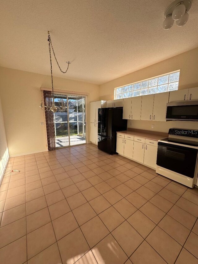 kitchen featuring black fridge, decorative light fixtures, white electric stove, white cabinets, and light tile patterned flooring