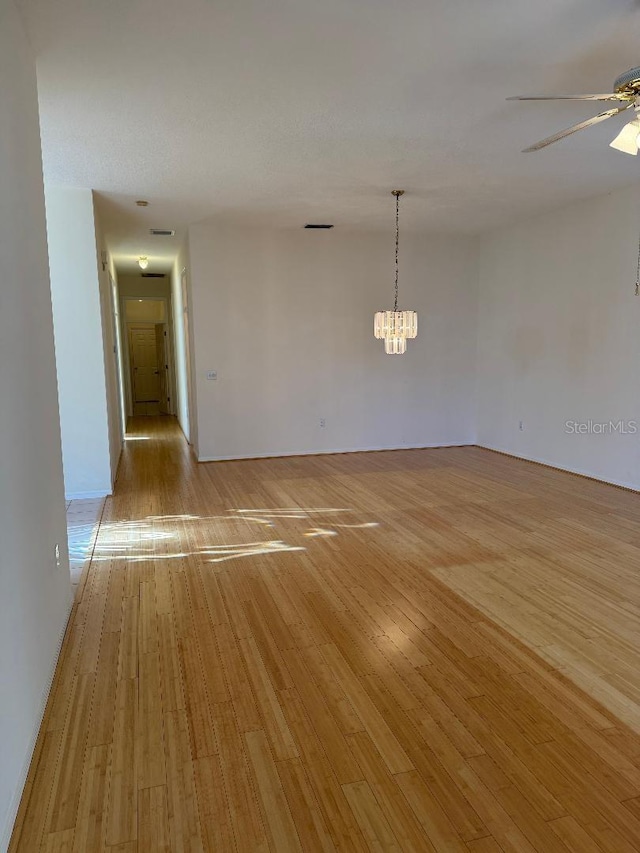 unfurnished room featuring a chandelier and light wood-type flooring