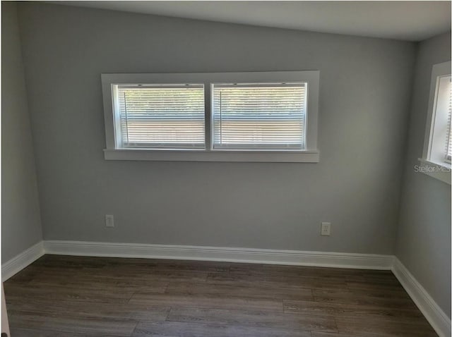 spare room with dark hardwood / wood-style flooring and plenty of natural light