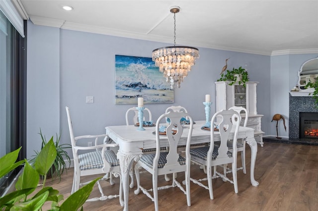 dining room with dark wood-type flooring, crown molding, a fireplace, and a chandelier