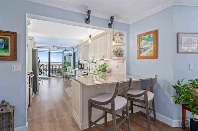 kitchen featuring dark hardwood / wood-style floors, kitchen peninsula, pendant lighting, a breakfast bar area, and ornamental molding