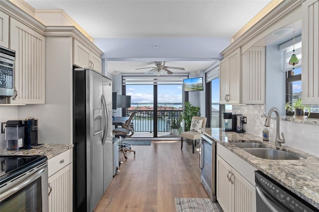 kitchen with backsplash, cream cabinets, sink, light hardwood / wood-style floors, and stainless steel appliances