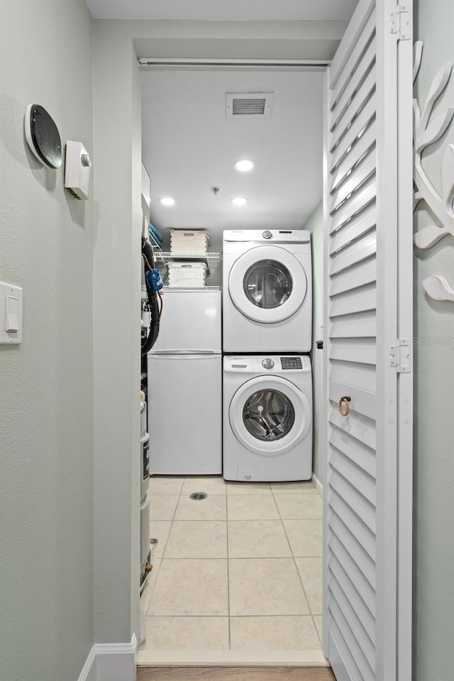 washroom featuring light tile patterned flooring and stacked washer / dryer