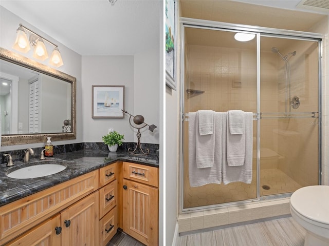 bathroom featuring hardwood / wood-style floors, vanity, toilet, and a shower with shower door