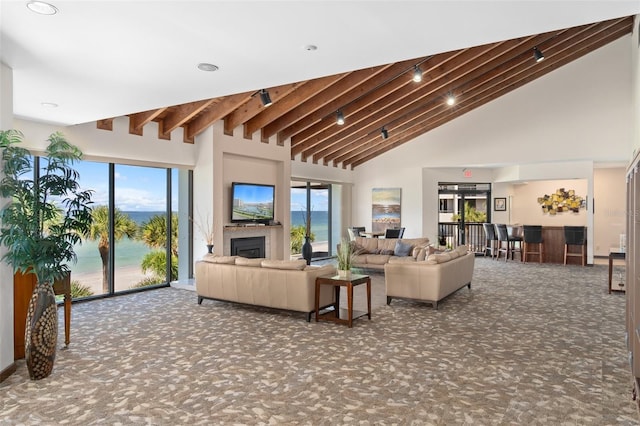 living room featuring beam ceiling, high vaulted ceiling, and dark carpet