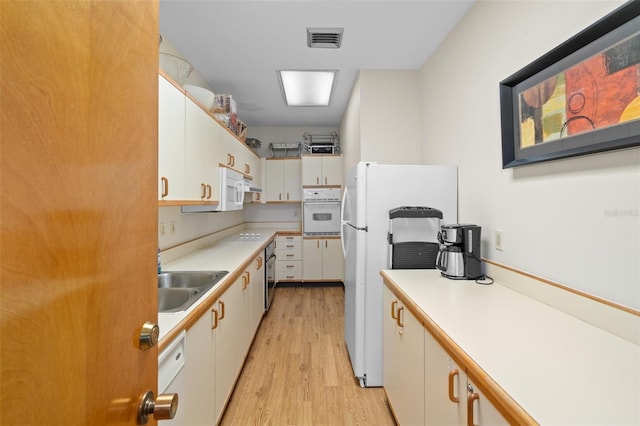 kitchen featuring white cabinets, white appliances, light hardwood / wood-style flooring, and sink