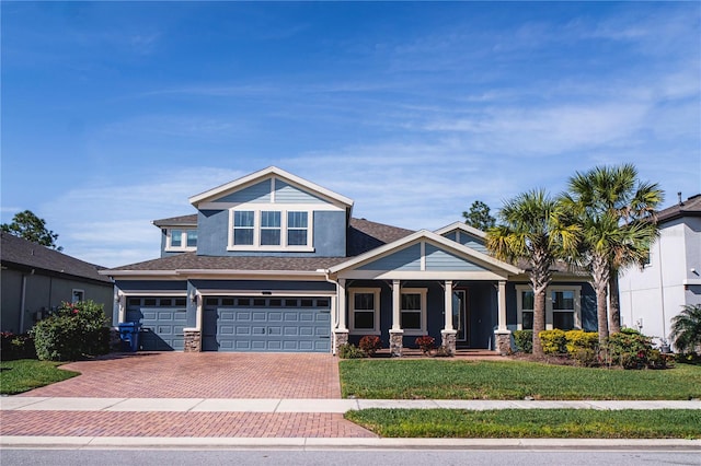 view of front of property featuring covered porch, a garage, and a front yard