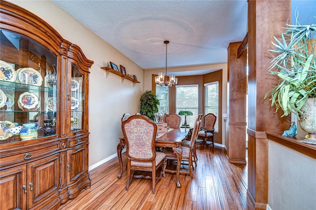 dining space featuring a textured ceiling, an inviting chandelier, and light hardwood / wood-style flooring