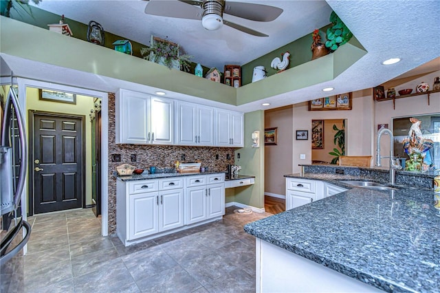 kitchen featuring a high ceiling, sink, white cabinets, and backsplash