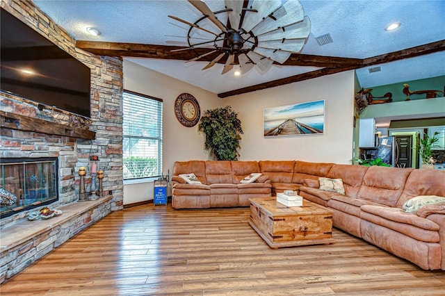 living room with ceiling fan, a textured ceiling, light hardwood / wood-style flooring, and beamed ceiling