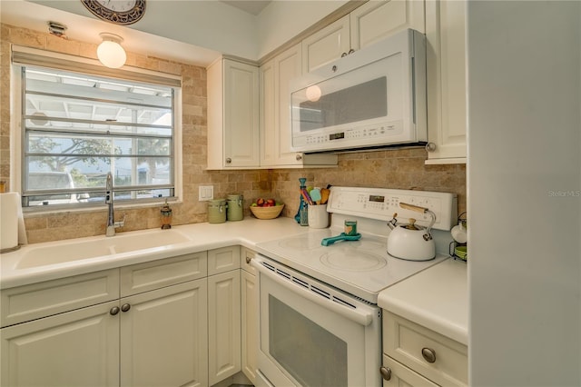 kitchen with backsplash, white cabinets, white appliances, and sink