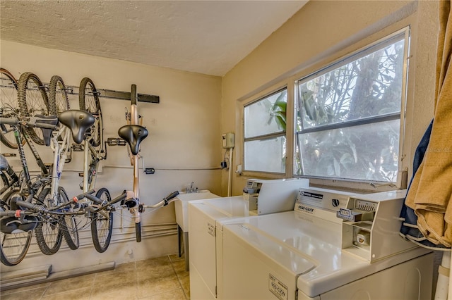 clothes washing area with light tile patterned floors, a textured ceiling, and washer and clothes dryer