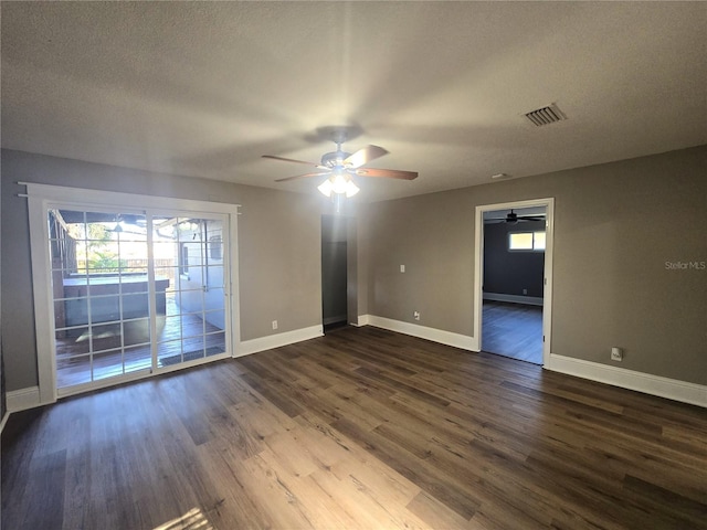 spare room with dark wood-style floors, visible vents, and a healthy amount of sunlight