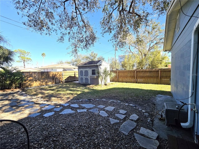 view of yard featuring a shed, a fenced backyard, and an outdoor structure