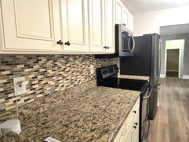 kitchen featuring tasteful backsplash, appliances with stainless steel finishes, dark stone counters, and wood finished floors