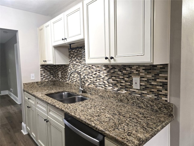 kitchen with dark wood finished floors, white cabinets, a sink, dark stone countertops, and dishwashing machine