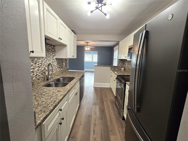 kitchen featuring dark stone counters, stainless steel appliances, a sink, and white cabinets